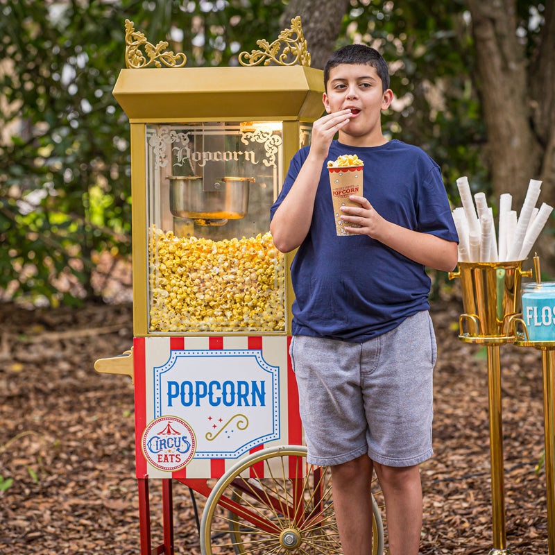 boy eating popcorn in front of Standard Popcorn cart